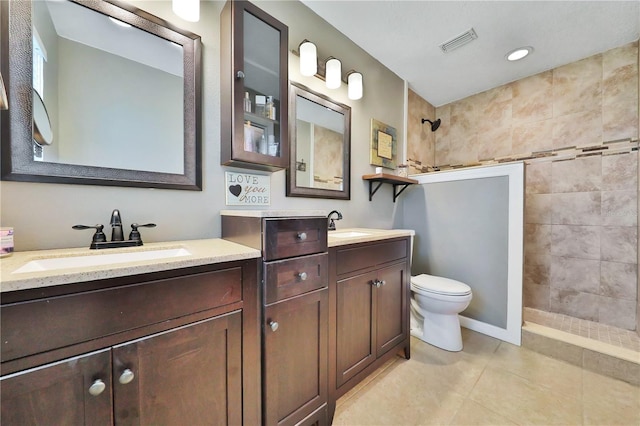 bathroom featuring vanity, tile patterned floors, toilet, and tiled shower