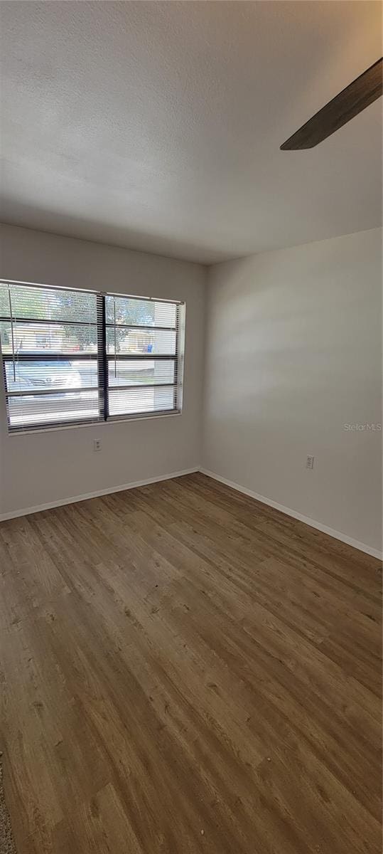 spare room with dark hardwood / wood-style flooring, ceiling fan, and a textured ceiling