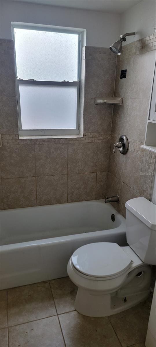 bathroom featuring tiled shower / bath combo, a wealth of natural light, tile patterned floors, and toilet