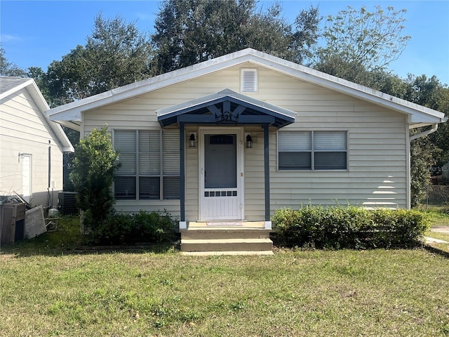 bungalow-style house with a front yard and central air condition unit