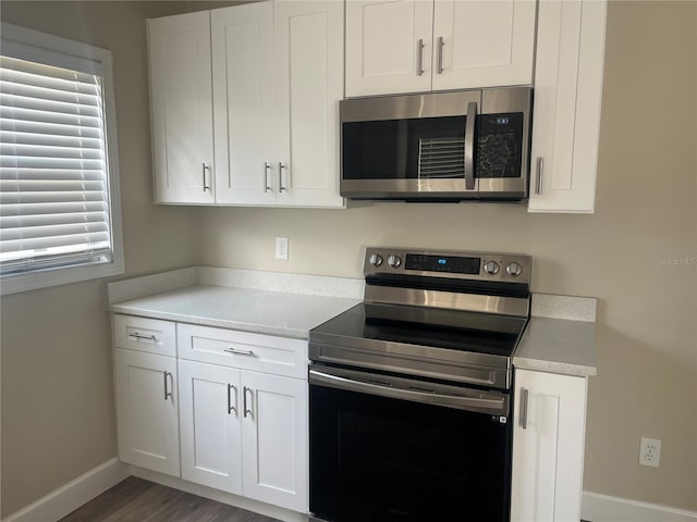 kitchen featuring white cabinetry, appliances with stainless steel finishes, dark wood-type flooring, and a wealth of natural light