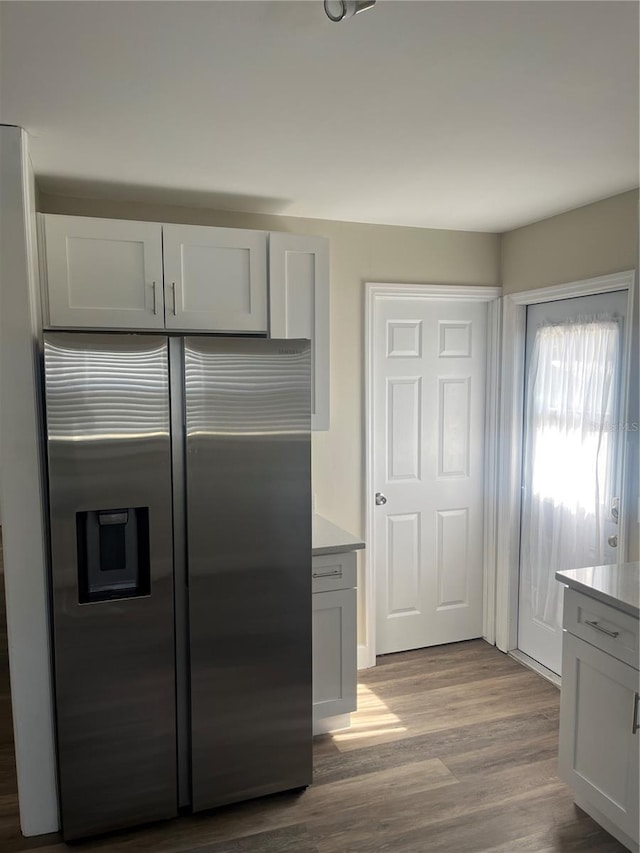 kitchen with white cabinetry, stainless steel fridge, and light hardwood / wood-style flooring