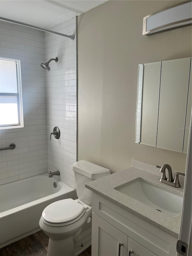 full bathroom featuring vanity, hardwood / wood-style flooring, tiled shower / bath combo, and toilet