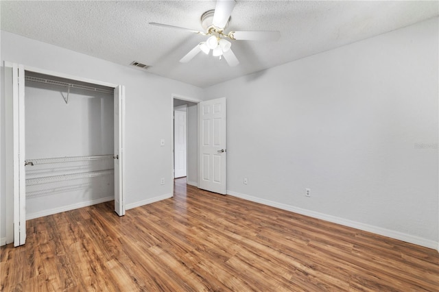 unfurnished bedroom with ceiling fan, hardwood / wood-style floors, a textured ceiling, and a closet