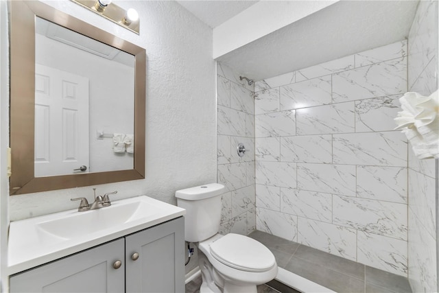 bathroom featuring vanity, toilet, and a tile shower