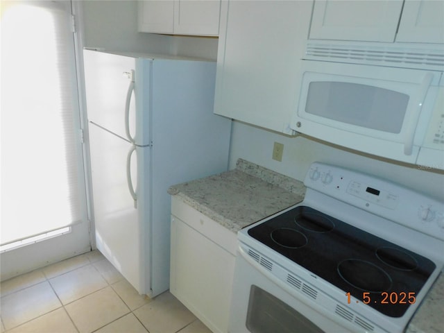 kitchen with light stone counters, white appliances, light tile patterned floors, and white cabinets