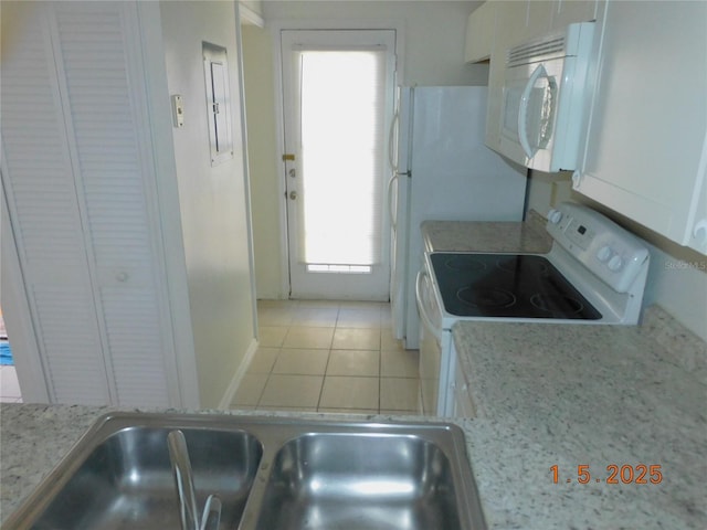 kitchen featuring sink, white cabinets, light tile patterned floors, light stone counters, and white appliances