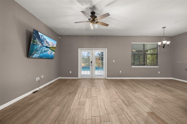 empty room featuring a textured ceiling, baseboards, wood finished floors, and french doors