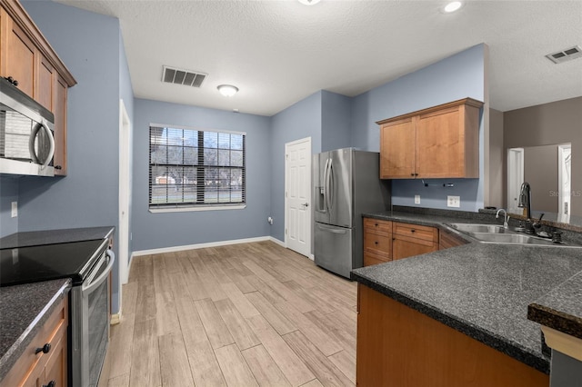 kitchen featuring stainless steel appliances, dark countertops, a sink, and visible vents