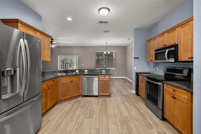 kitchen with light wood finished floors, visible vents, appliances with stainless steel finishes, a peninsula, and a sink