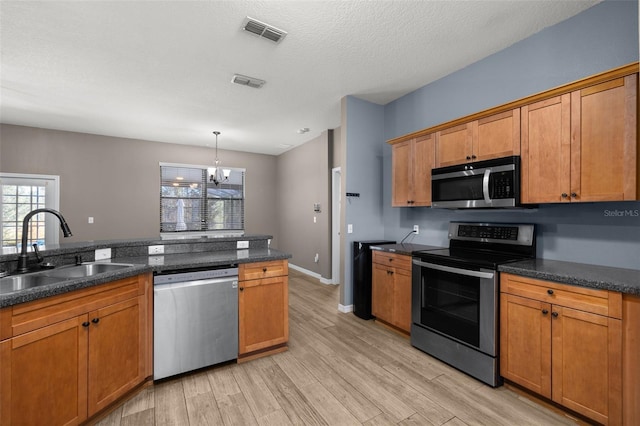 kitchen with light wood finished floors, visible vents, stainless steel appliances, and a sink