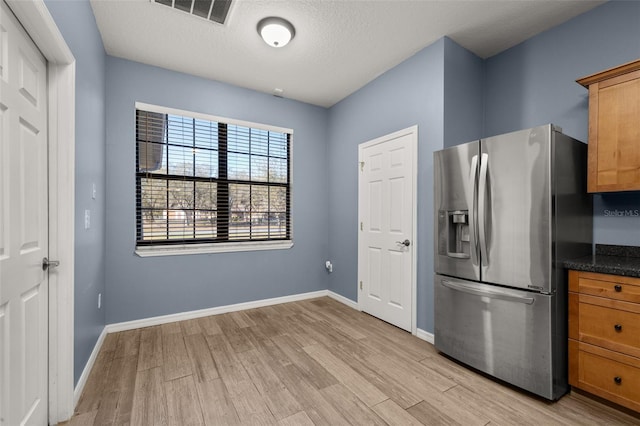 kitchen featuring baseboards, visible vents, stainless steel refrigerator with ice dispenser, and light wood finished floors