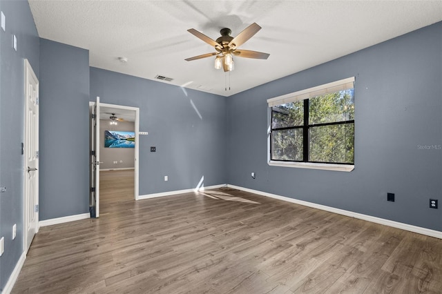 unfurnished room with ceiling fan, baseboards, and wood finished floors