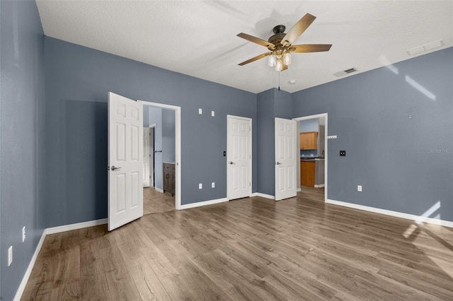 unfurnished bedroom with connected bathroom, baseboards, and wood finished floors