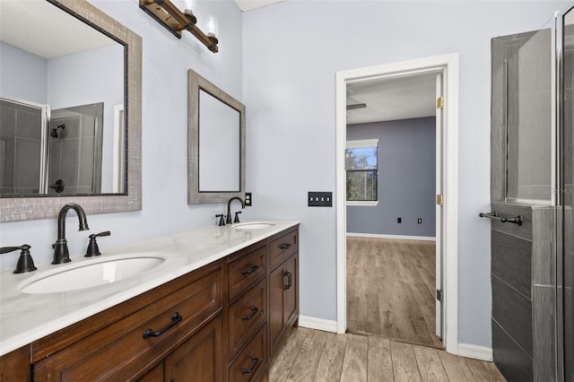 bathroom featuring a tile shower, double vanity, wood finished floors, and a sink