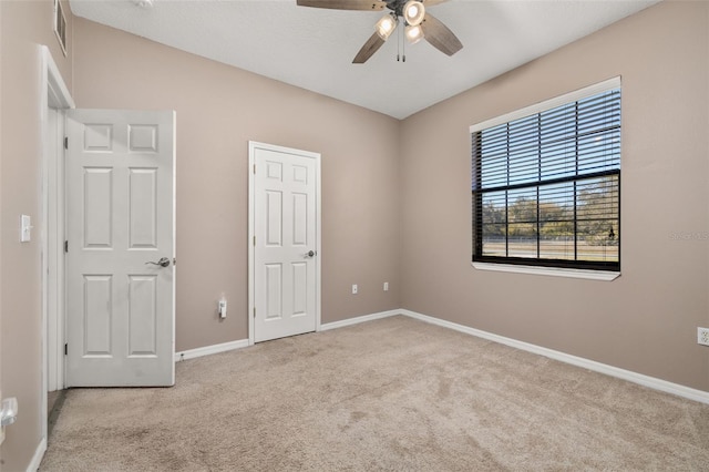 empty room featuring ceiling fan, carpet flooring, visible vents, and baseboards