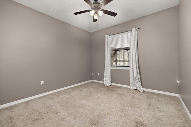 carpeted spare room featuring baseboards and a ceiling fan