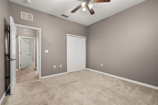 unfurnished bedroom featuring light carpet, visible vents, and a closet