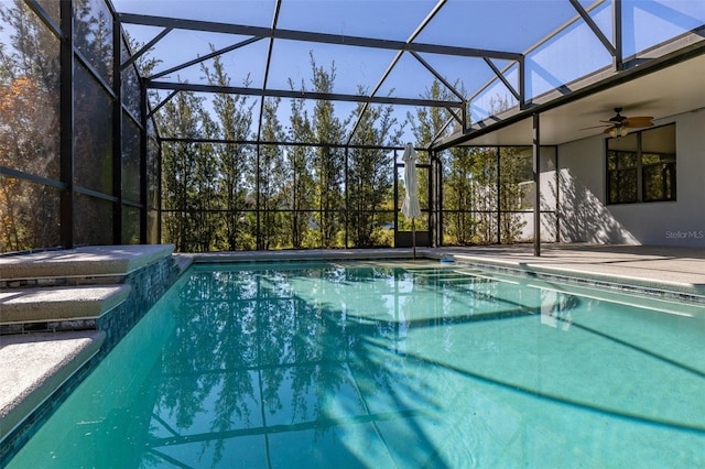 outdoor pool with a ceiling fan, a patio area, and glass enclosure