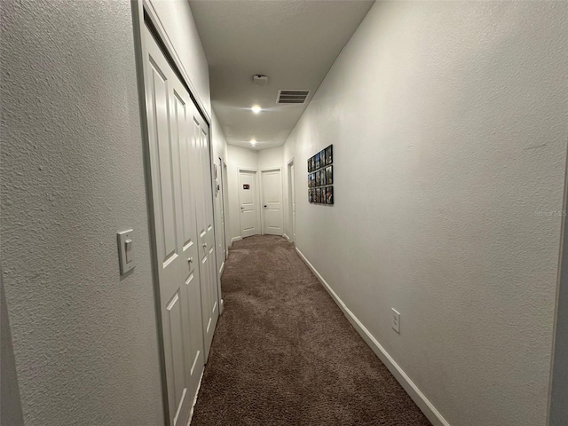 hallway with dark colored carpet