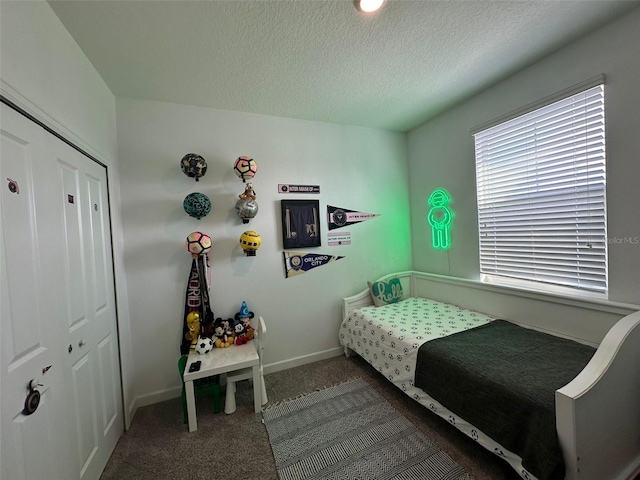 bedroom featuring a textured ceiling and dark carpet