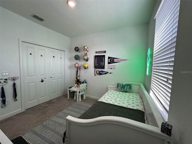 carpeted bedroom with a closet and a textured ceiling