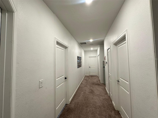 hall with dark colored carpet