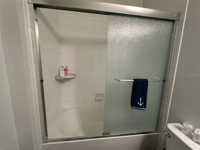 bathroom featuring bath / shower combo with glass door and toilet