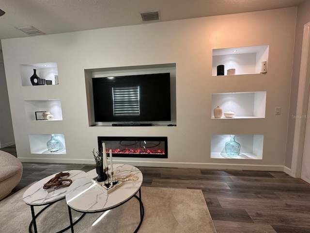 living room featuring built in shelves and dark hardwood / wood-style flooring