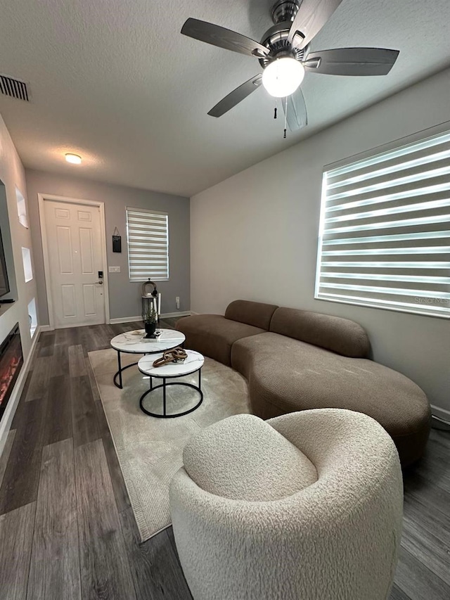 living room with ceiling fan, dark wood-type flooring, and a textured ceiling