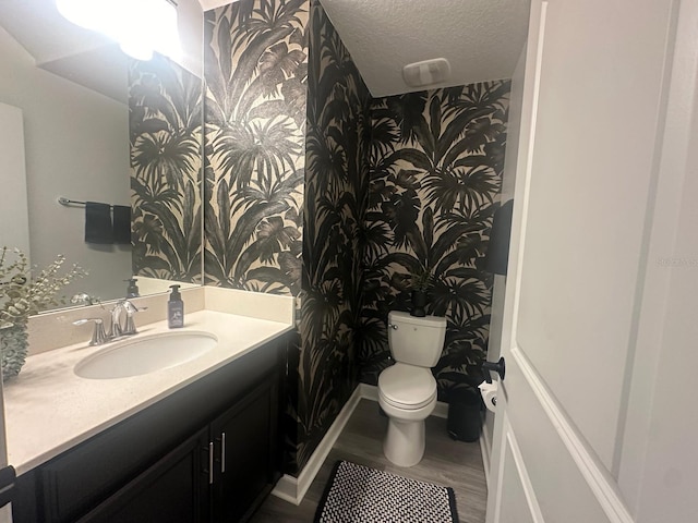 bathroom featuring vanity, wood-type flooring, toilet, and a textured ceiling