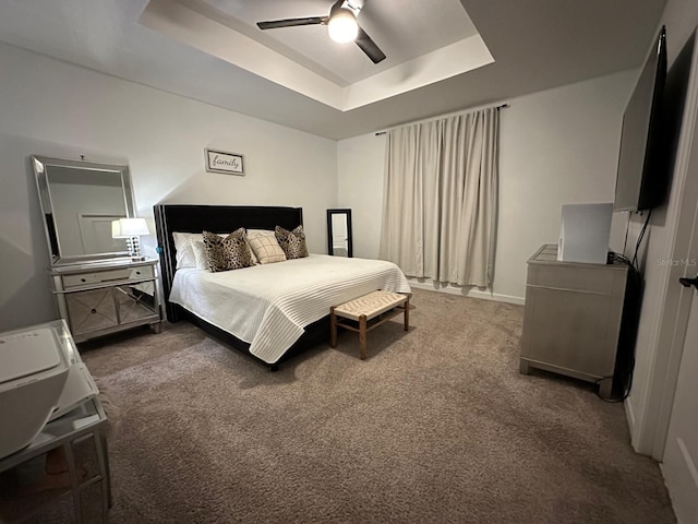 bedroom featuring dark carpet, a raised ceiling, and ceiling fan