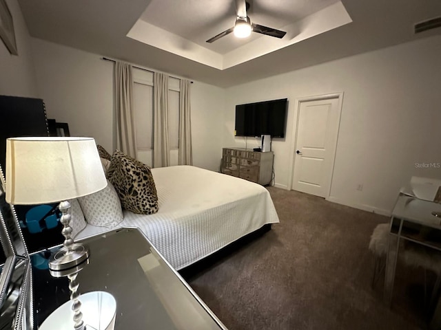 carpeted bedroom featuring a raised ceiling and ceiling fan