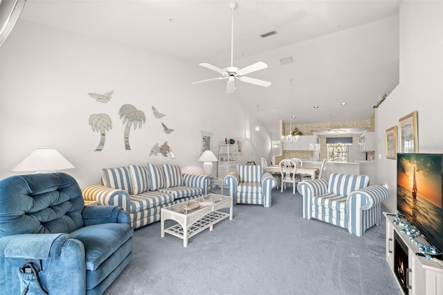 carpeted living room with ceiling fan and a towering ceiling