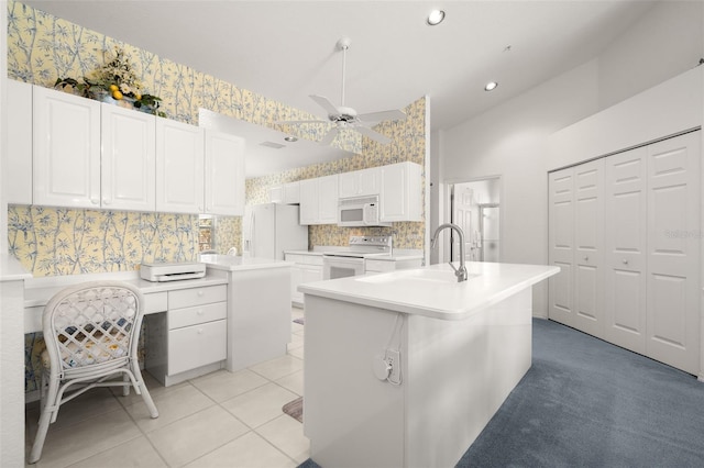 kitchen featuring white cabinetry, white appliances, sink, and an island with sink