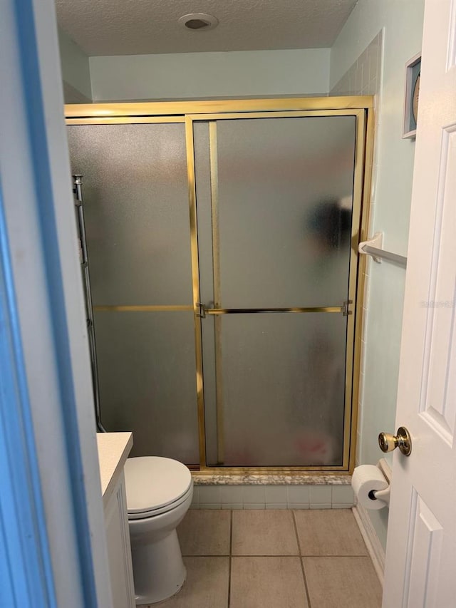 bathroom featuring tile patterned flooring, vanity, a textured ceiling, a shower with shower door, and toilet