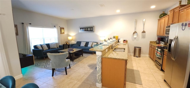 kitchen featuring light tile patterned flooring, sink, a kitchen bar, light stone counters, and stainless steel appliances