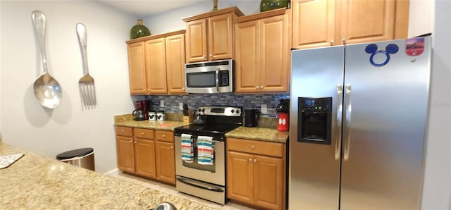 kitchen with light stone counters, hanging light fixtures, backsplash, and appliances with stainless steel finishes