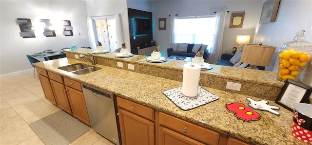 kitchen with light tile patterned flooring, stainless steel dishwasher, light stone countertops, and sink