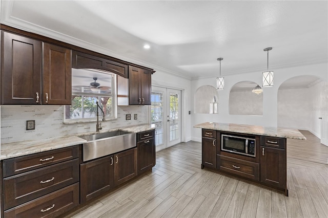 kitchen featuring built in microwave, sink, decorative light fixtures, dark brown cabinets, and backsplash