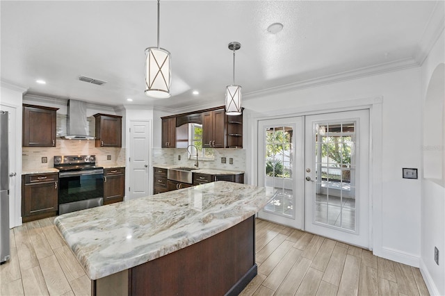 kitchen featuring decorative light fixtures, dark brown cabinets, wall chimney exhaust hood, and stainless steel electric range oven