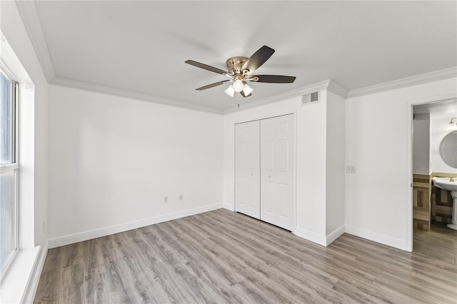 unfurnished bedroom featuring crown molding, a closet, ceiling fan, and light wood-type flooring