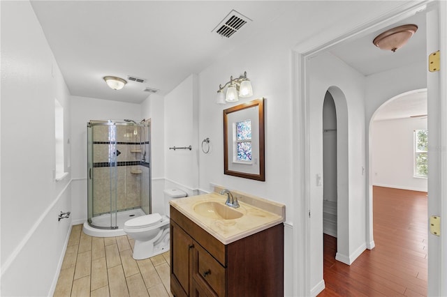 bathroom featuring vanity, hardwood / wood-style floors, a shower with door, and toilet