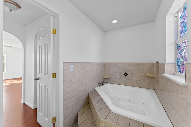 bathroom with wood-type flooring and a relaxing tiled tub