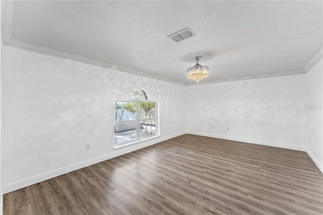 empty room featuring ornamental molding, wood finished floors, visible vents, and baseboards