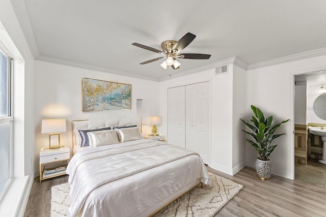 bedroom featuring visible vents, connected bathroom, wood finished floors, crown molding, and a closet