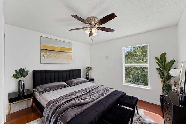 bedroom featuring a ceiling fan, a textured ceiling, baseboards, and wood finished floors