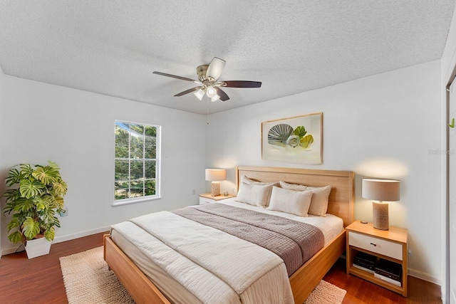 bedroom with ceiling fan, a textured ceiling, baseboards, and wood finished floors