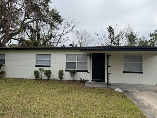 ranch-style house featuring a front lawn and concrete block siding