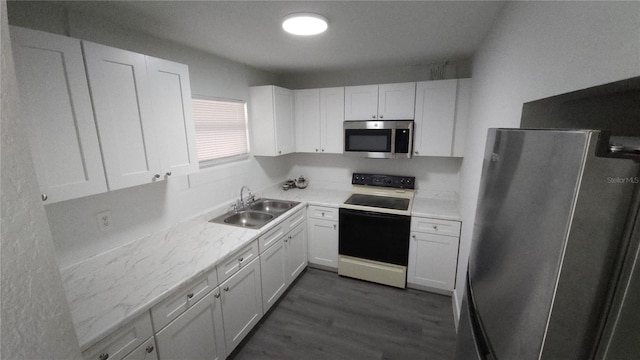 kitchen with stainless steel appliances, dark wood-type flooring, a sink, white cabinetry, and light countertops